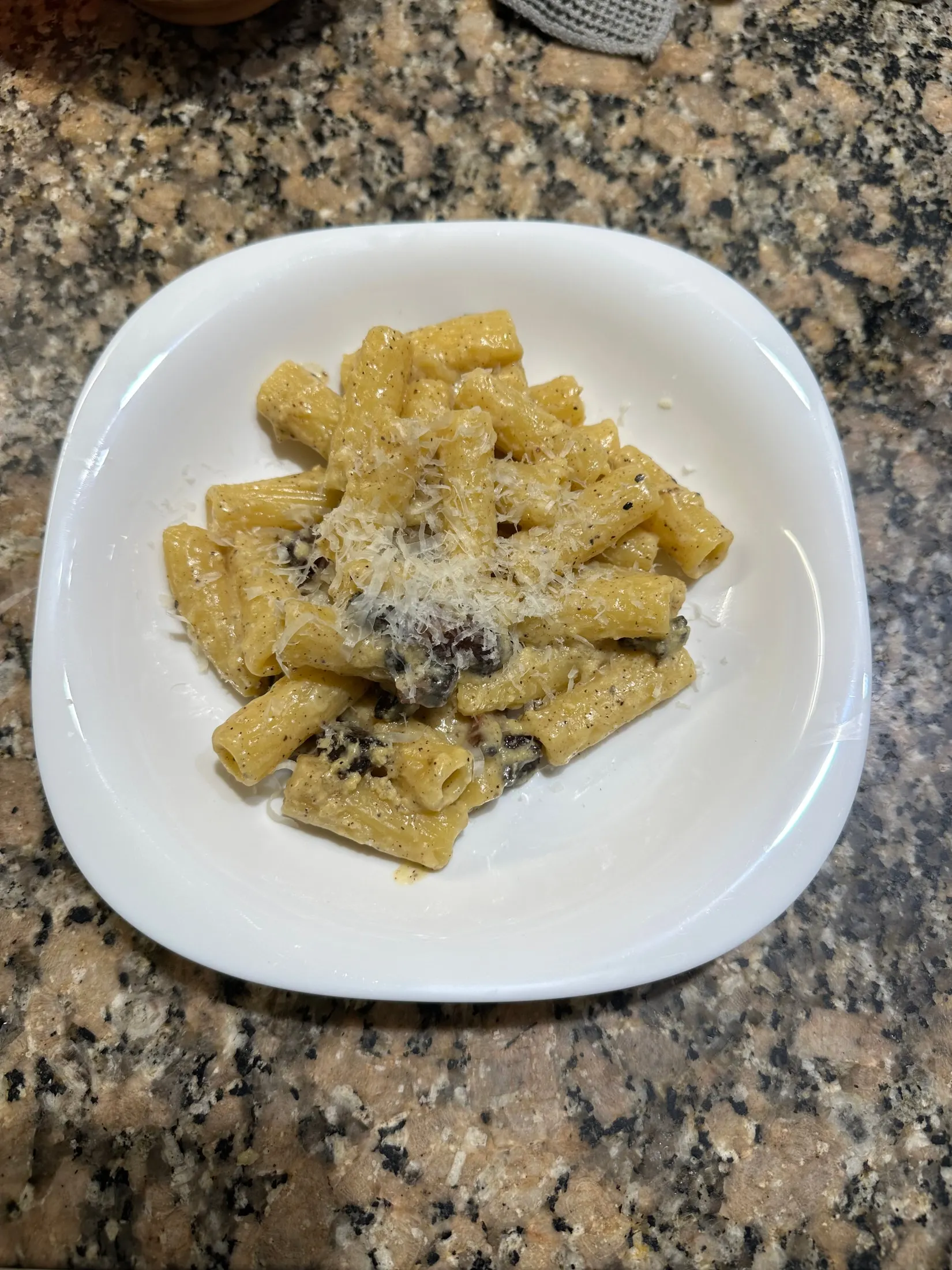 Plato de carbonara servido, con pecorino y pimienta negra