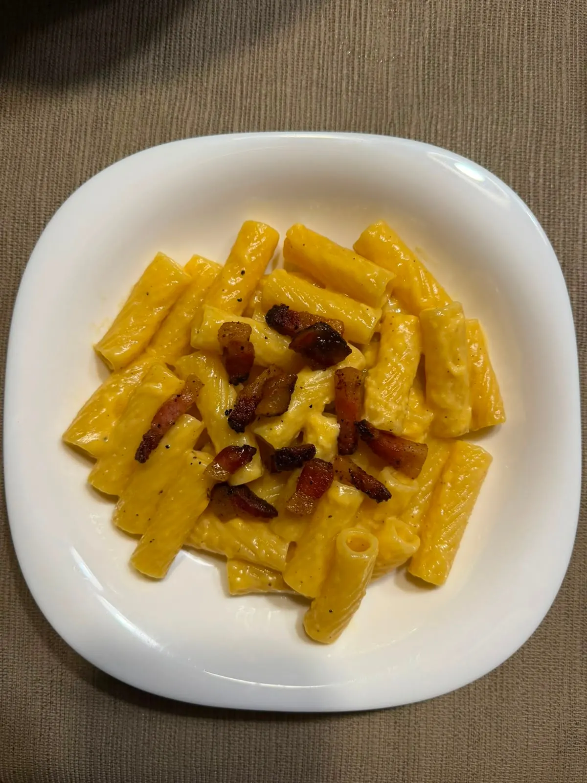 Plato de carbonara con rigatoni, la salsa envolviendo la pasta
