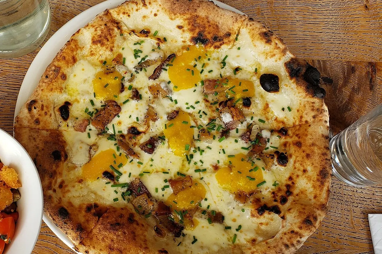 Pizza con guanciale, yema de huevo y mozzarella, recién salida del horno