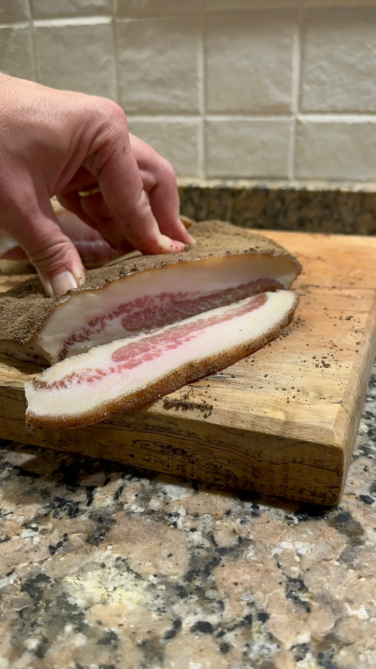 Pieza de guanciale sobre tabla de madera, cortándose con cuchillo