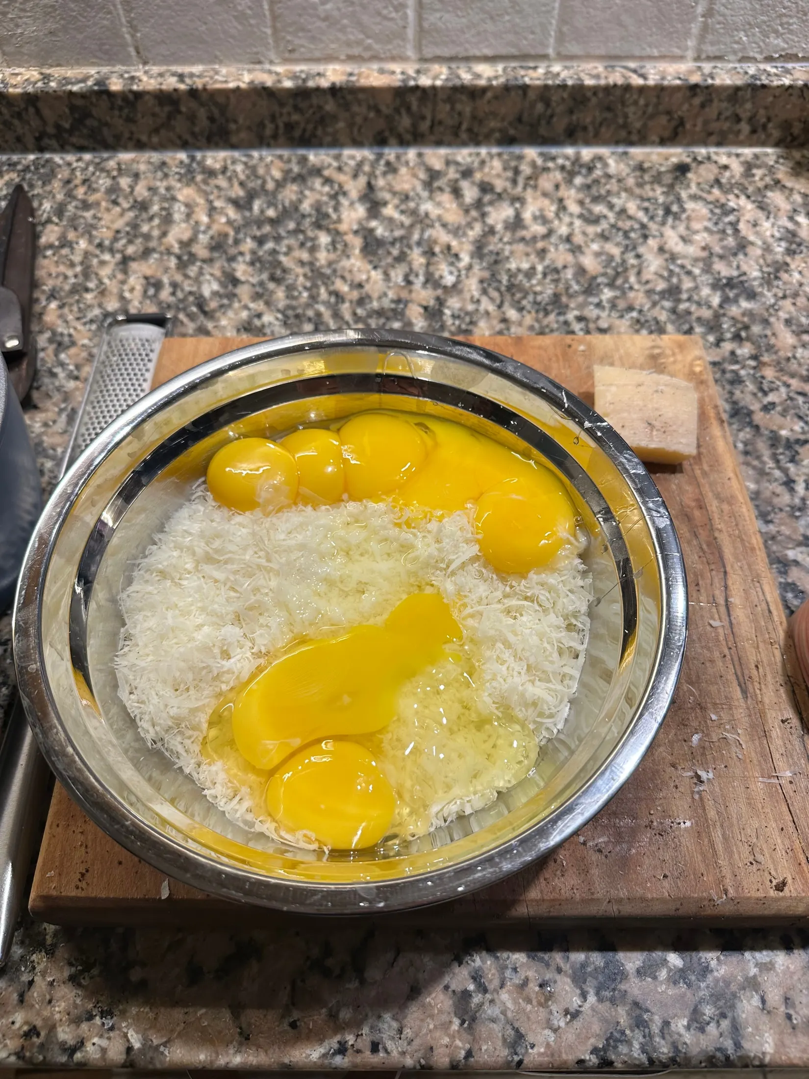 Yemas de huevo sobre pecorino recién rallado, en un bowl de acero